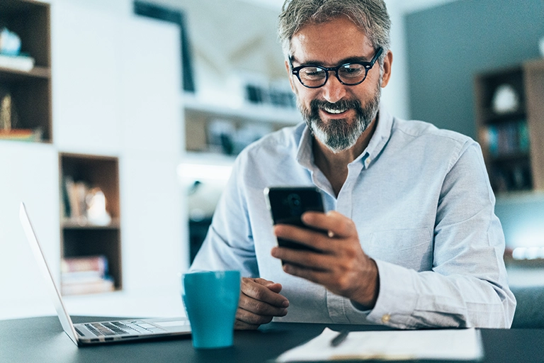 Man with glasses and phone at desk